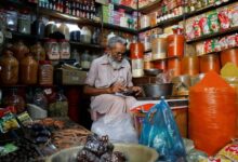 A shopkeeper uses a calculator while selling spices and grocery items along a shop in Karachi. — Reuters/File