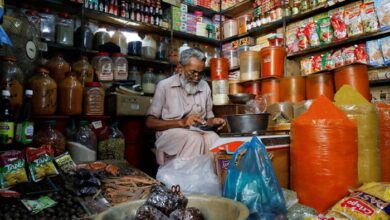 A shopkeeper uses a calculator while selling spices and grocery items along a shop in Karachi. — Reuters/File