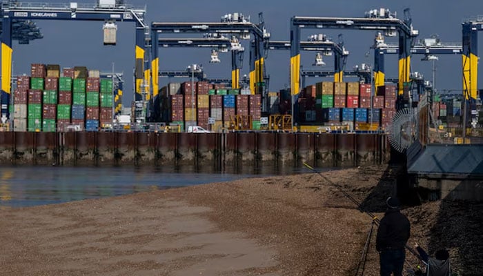 A man, while fishing, points towards shipping containers at the Port of Felixstowe in Felixstowe, Britain, February 17, 2025. — Reuters