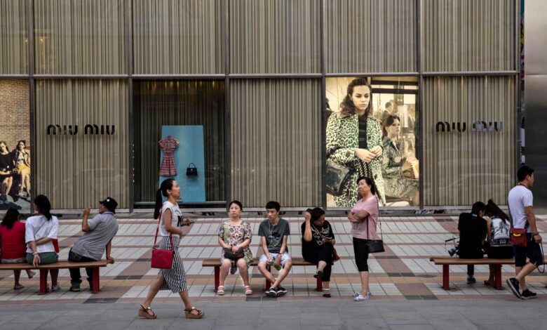 Chinese shoppers sit in front of a luxury store in an upscale shopping district in Beijing. Photo: Getty Images