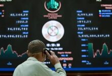 A broker talks on phone as he looks at an index board showing the latest share prices at the PSX in Karachi on February 10, 2023. — AFP