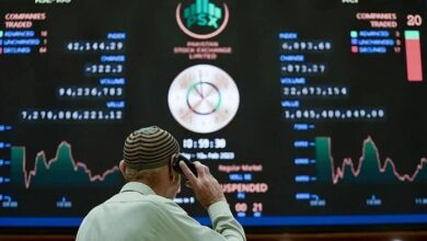 A broker talks on phone as he looks at an index board showing the latest share prices at the PSX in Karachi on February 10, 2023. — AFP