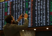 A man takes a photo of the electronic board at the Pakistan Stock Exchange, in Karachi November 28, 2023. — Reuters