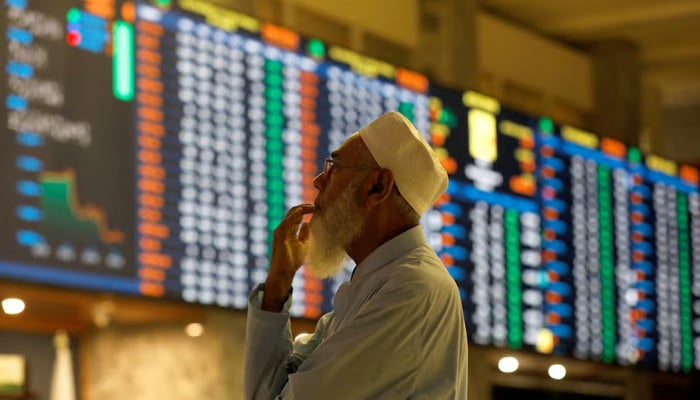 A stock broker reacts while monitoring the market on the electronic board displaying share prices during trading session at the Pakistan Stock Exchange, in Karachi, July 3, 2023. — Reuters