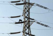 A technician works on porcelain insulators on power transmission tower in Karachi. — Reuters/File