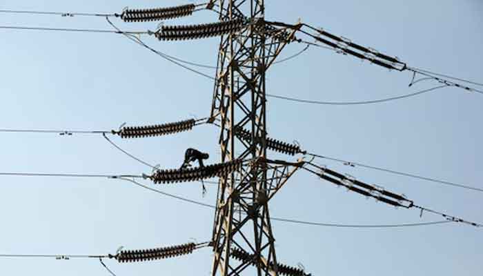 A technician works on porcelain insulators on power transmission tower in Karachi. — Reuters/File