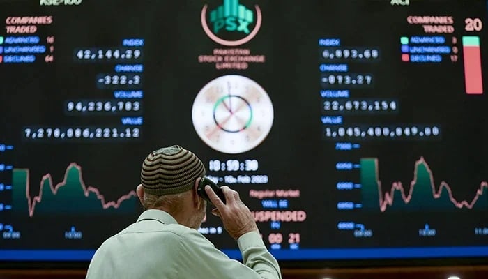 A broker talks on the phone as he looks at an index board showing the latest share prices at the PSX in Karachi on February 10, 2023. — AFP