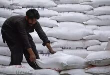 A labourer unloads sacks of sugar from a supply truck at the main wholesale market in Karachi. — Reuters/ File