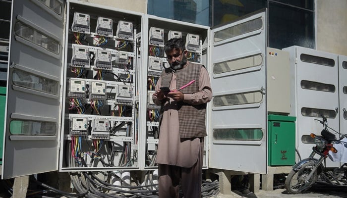 An employee of the state-run Islamabad Electric Supply Company takes a meter reading with his smartphone at a commercial building in Islamabad. —AFP/File