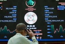 A broker talks on phone as he looks at an index board showing the latest share prices at the PSX in Karachi on February 10, 2023. — AFP